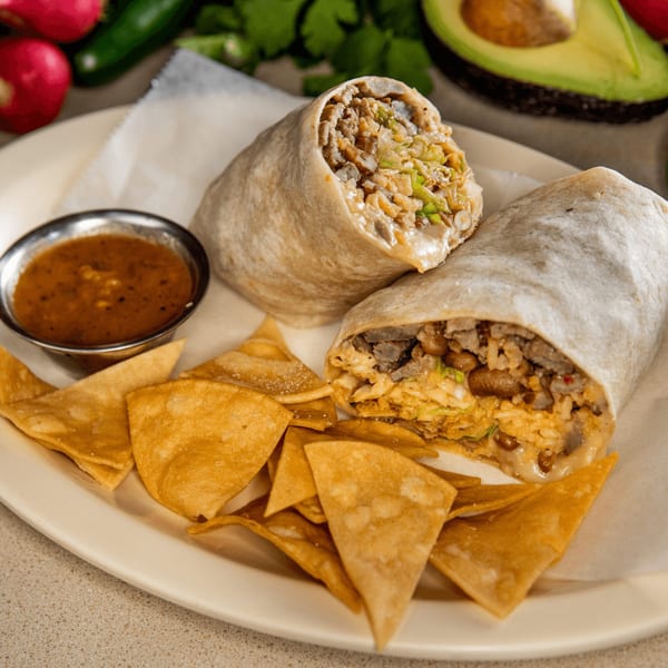 Two Homemade Taqueria burritos, one cut in half, with tortilla chips and a side of salsa.