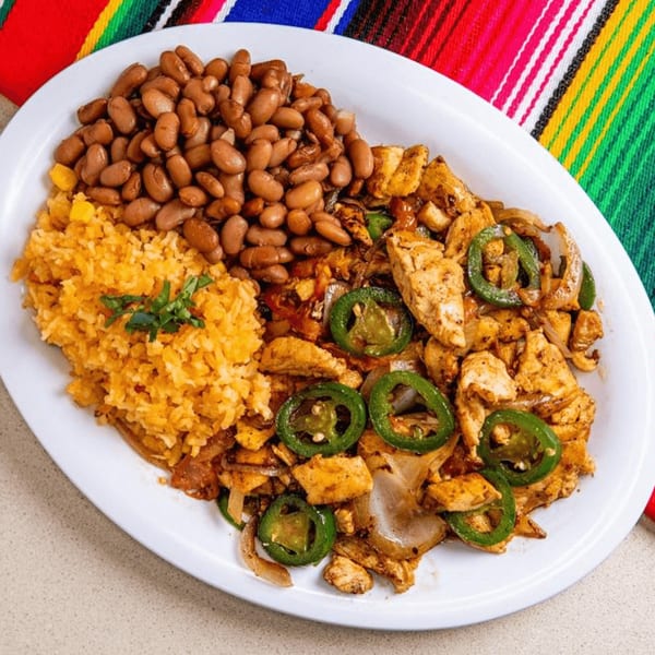 A Mexican dish with chicken fajitas, rice, and beans on a white plate with a colorful striped background.